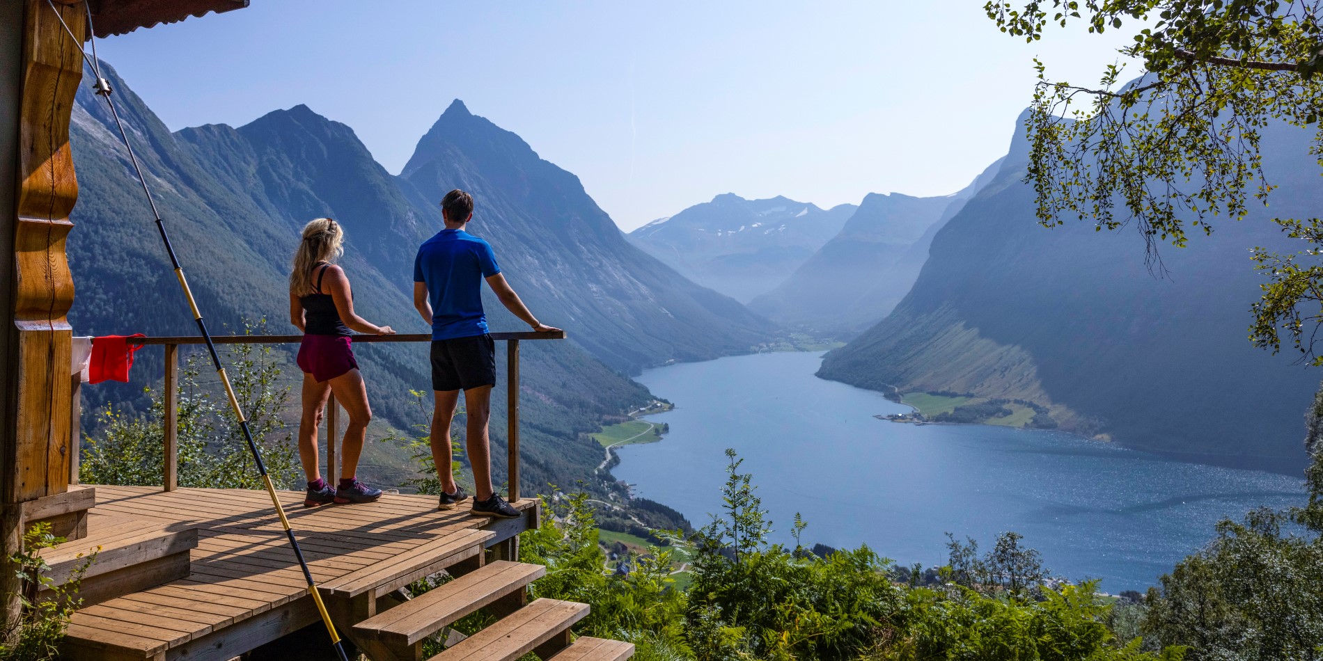 Ett par står vid en utsiktsplats och blickar ut över Hjørundfjorden. Norges västkust