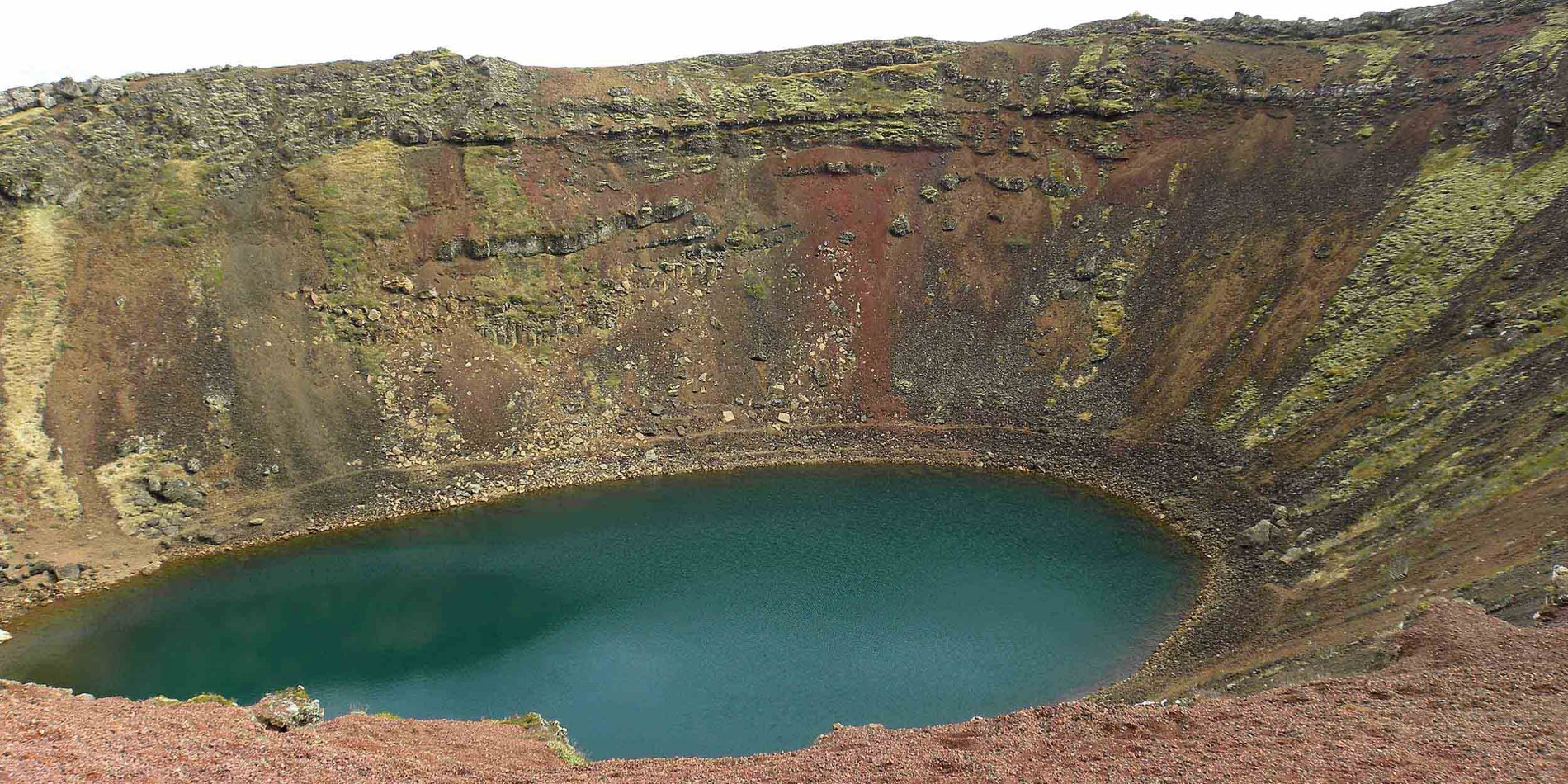 Vatten bredvid klippan med stort hål i bakgrunden