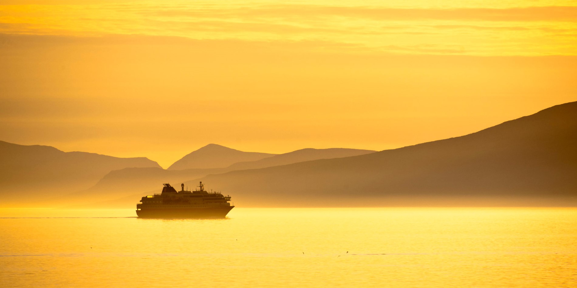 Hurtigruten seglar under en av de eviga sommardagarna i Norge