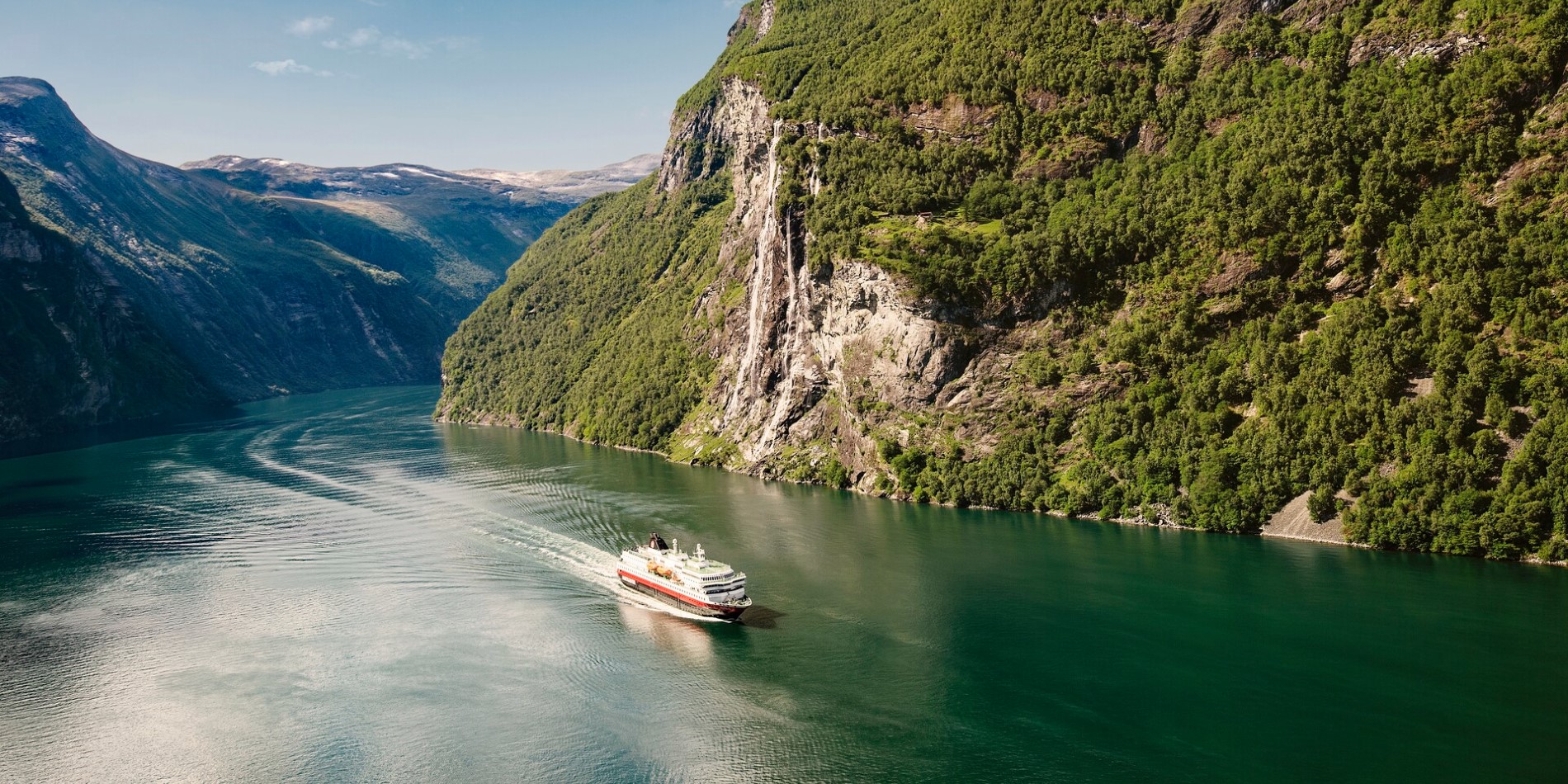 A Hurtigruten cruise ship sailing through the Geirangerfjord 